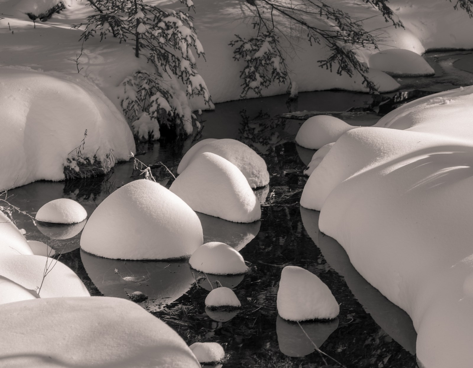 Rounded caps of snow sit above a narrow dark stream.