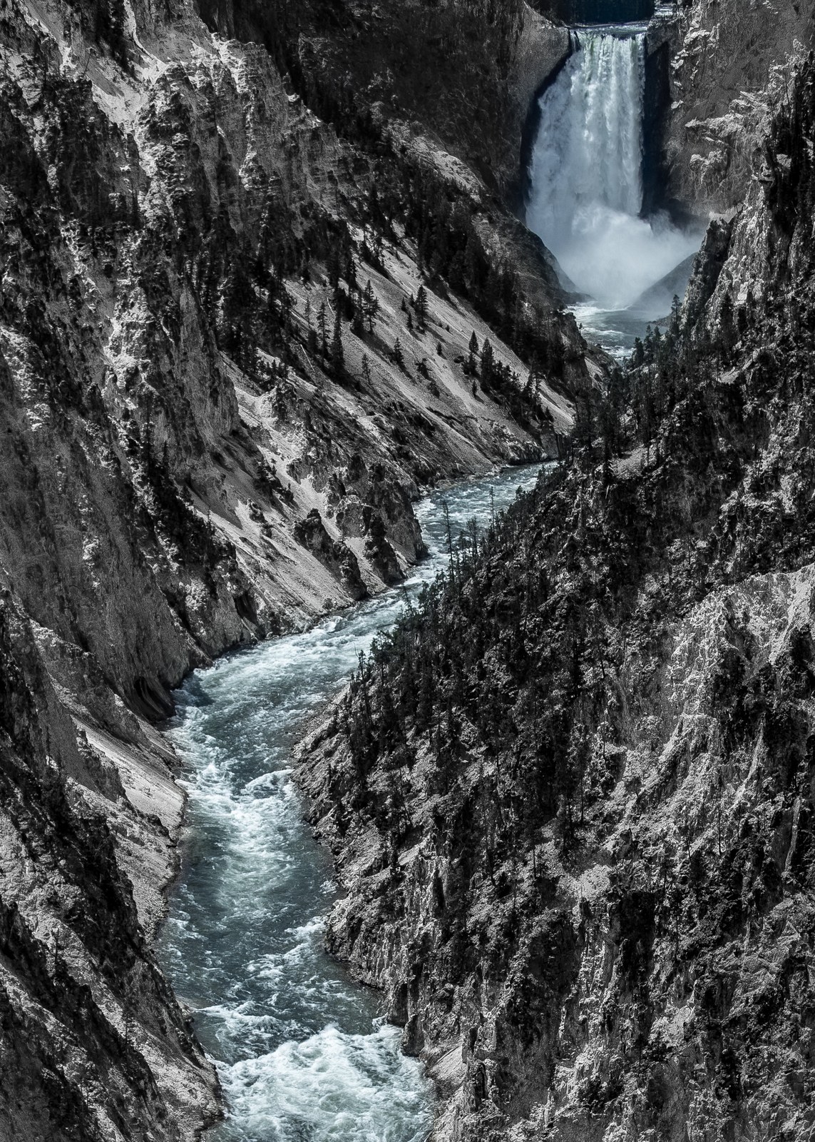 A tall waterfall pouring into a narrow rocky canyon.