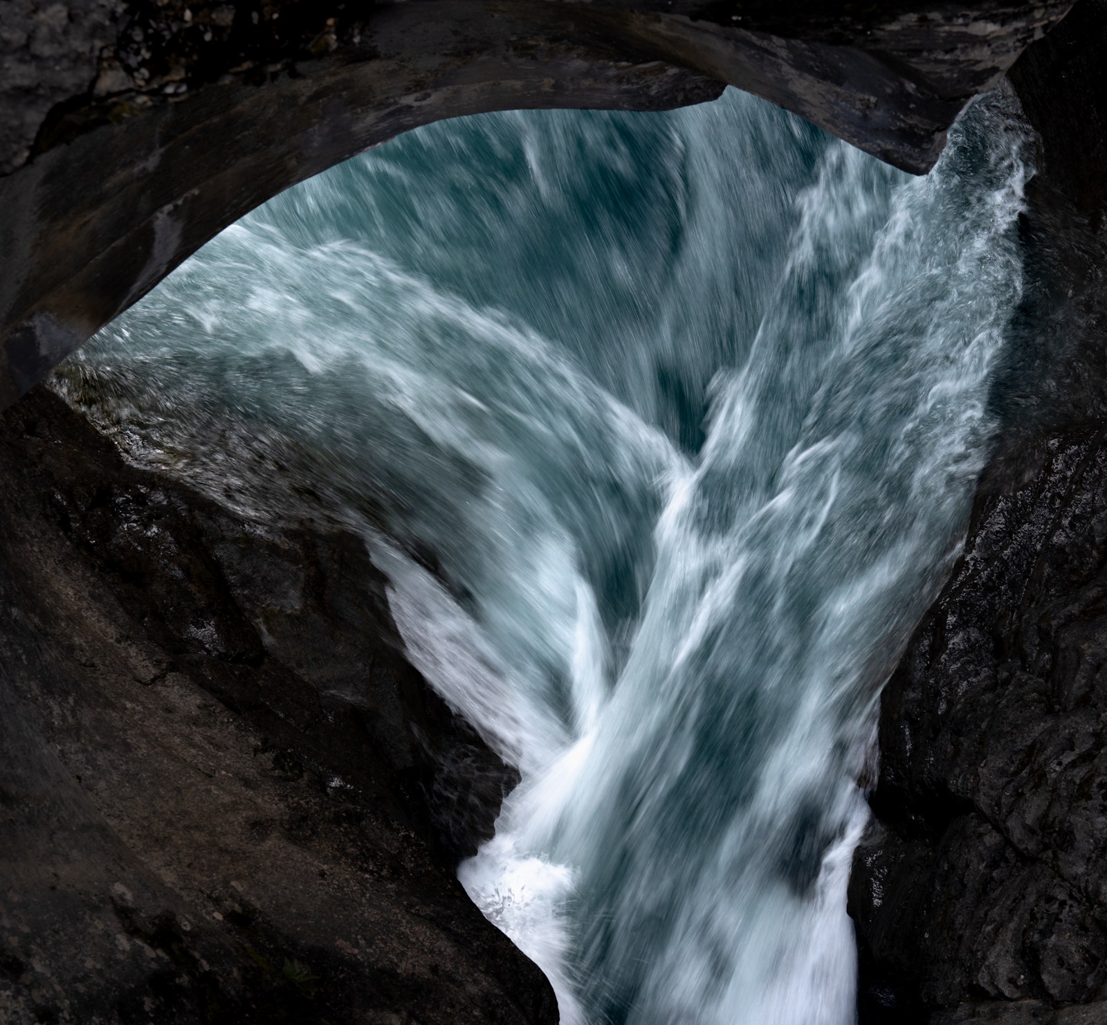 White streaks of water converge inside a dark stone opening.